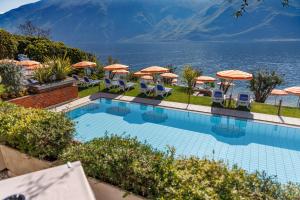 a swimming pool with chairs and umbrellas at Hotel Lido Lakefront in Limone sul Garda