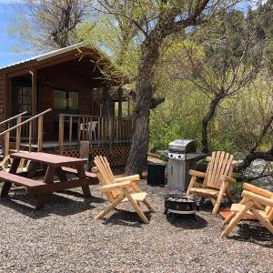 a group of picnic tables and chairs in front of a cabin at Virginia Creek Settlement in Bridgeport