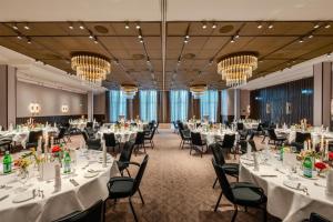 a banquet hall with white tables and chairs and chandeliers at Radisson Blu Senator Hotel, Lübeck in Lübeck +118 photos