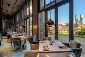 a restaurant with tables and chairs and large windows at Radisson Blu Senator Hotel, Lübeck in Lübeck