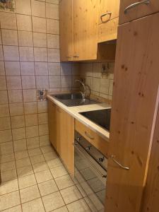 a kitchen with wooden cabinets and a sink at Campiglio Monolocale Cima Tosa in Madonna di Campiglio