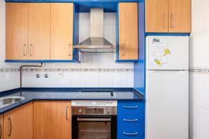 a kitchen with blue cabinets and a white refrigerator at Jardín del Golf2 9 1A in Novo Sancti Petri +18 photos