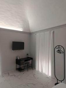 a white room with a desk and a tv on the wall at Vulcano Rooms 1 in Catania