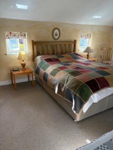 a bedroom with a bed and two tables and two windows at The Old Post Office, Hilton in Huntingdon