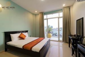 a bedroom with a bed and a desk and a window at Nét Việt House Hotel Market & Bridge Centre Soc Trang in Soc Trang