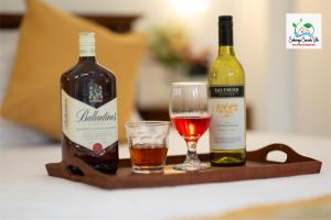 two bottles of wine and a glass on a tray at Sinharaja Cascade Villa in Deniyaya
