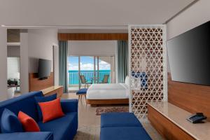 a hotel room with a blue couch and a bed at Hilton Cancun Mar Caribe All-Inclusive Resort in Cancún