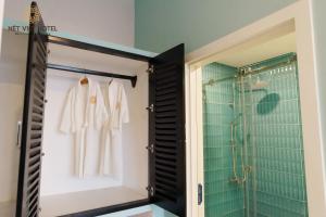 a bathroom with a walk in shower and white robes at Nét Việt House Hotel Market & Bridge Centre Soc Trang in Soc Trang +42 photos