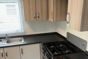 a kitchen with a stove top oven next to a sink at Caravan- Sleeps 6 2 Bedrooms - Thurston Manor in Dunbar