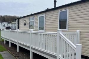 a house with a white fence and a house at Caravan- Sleeps 6 2 Bedrooms - Thurston Manor in Dunbar