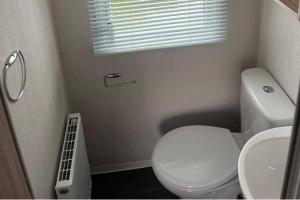 a bathroom with a white toilet and a sink at Caravan- Sleeps 6 2 Bedrooms - Thurston Manor in Dunbar