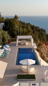 a pool with chairs and umbrellas next to the ocean at Okeanos Vine Luxury Villa in Athani