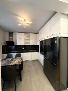 a kitchen with white cabinets and a black refrigerator at Eden apartments in Tivat