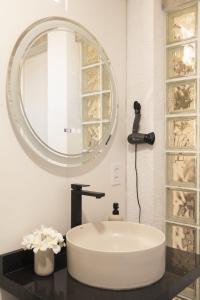 a bathroom with a white sink and a mirror at Golden Pipa House in Pipa