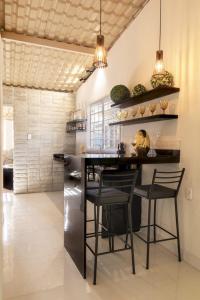 a kitchen with a black counter and chairs in it at Golden Pipa House in Pipa