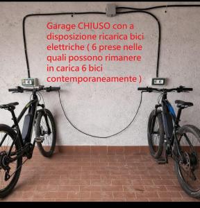 two bikes parked against a wall with a sign at Locazione turistica Cuore d'Altopiano ad Asiago con ricarica per E-Bike in Asiago