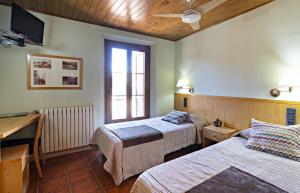 a bedroom with two beds and a desk and a window at Hostal Victor in Oliana