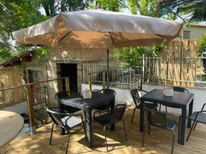 two tables and chairs under an umbrella on a deck at Villa BRUNI Wine Guest House in Montefalco