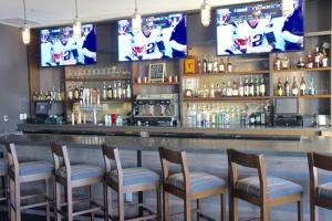 a bar with a row of chairs and televisions at Four Points by Sheraton Midland in Midland