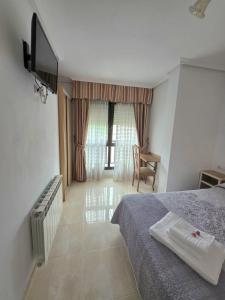 a bedroom with a bed and a television and a chair at Hostal Restaurante Piedra in Limpias