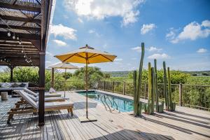 a deck with a pool with a table and an umbrella at Hotel Omún, San Miguel de Allende in Dolores Hidalgo