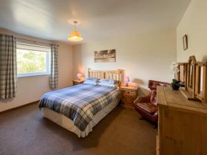a bedroom with a bed and a chair and a window at Uk47551 - Cree View Cottage in Newton Stewart
