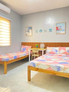 a bedroom with two beds and a table and a table at ZK Homestay in Puerto Princesa City