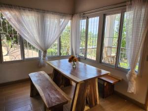 a wooden table and bench in a room with windows at Casa de Coral in Santa Lucía