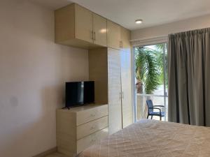 a bedroom with a bed and a tv and a window at Estudio Cerca del mar, en Puerto Aventuras #201 in Puerto Aventuras