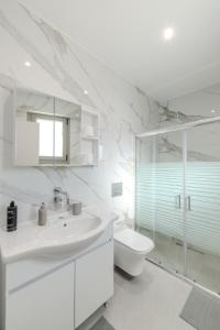 a white bathroom with a toilet and a sink at Villa Nazar in Xiropigado +34 photos
