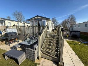 a house with a deck with two chairs and a grill at Sunset Serenity - 4 Sunset View in Crowle