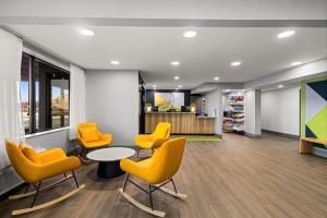 a waiting room with yellow chairs and a table at Spark By Hilton Fort Wayne in Fort Wayne