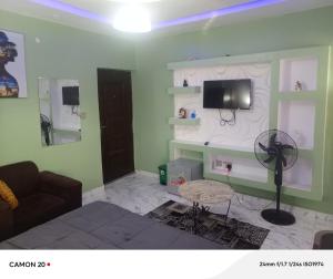 a living room with a couch and a tv on a wall at RichRoyal Hotels Ltd in Oruama