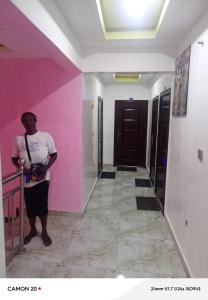 a woman standing in a hallway with a pink wall at RichRoyal Hotels Ltd in Oruama