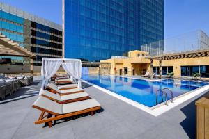 a hotel pool with two lounge chairs next to a building at DoubleTree by Hilton Jeddah - Alandalus Mall in Jeddah