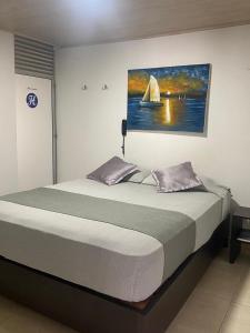 a bedroom with a bed with a painting of a sailboat at Hotel La Castellana in Manizales +54 photos