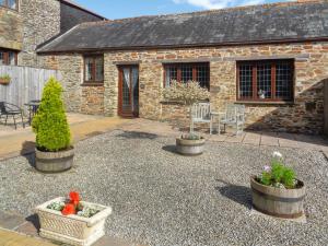 a patio with three potted plants in front of a building at Byre Cottage - Uk50028 in Liskeard