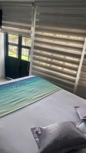 a bed in a room with a window with blinds at Hotel La Castellana in Manizales
