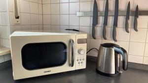 a microwave sitting on a kitchen counter with knives at Ferienwohnung Karl May in Lennestadt