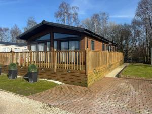a wooden cabin with a wooden fence in a yard at Cedar Lodge - 27 Sunset View in Crowle