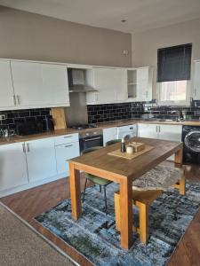 a kitchen with white cabinets and a wooden table at Sleep Eat Repeat Apartment in Macclesfield +11 photos