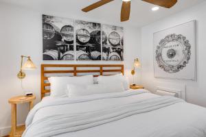 a bedroom with a large white bed and pictures on the wall at HIDEAWAY @ Speakeasy Inn Key West! in Key West