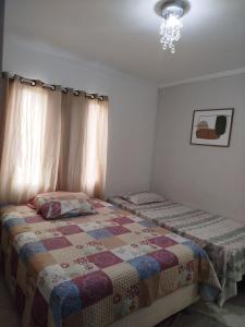 a bedroom with two beds and a chandelier at Casa Aconchego in São Carlos