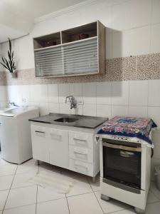 a white kitchen with a sink and a counter top at Casa Aconchego in São Carlos