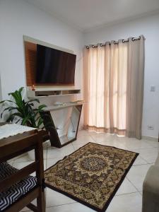 a living room with a flat screen tv and a rug at Casa Aconchego in São Carlos
