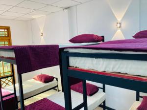 a room with three bunk beds with purple sheets and pillows at Ashi Hostel Sigiriya in Sigiriya