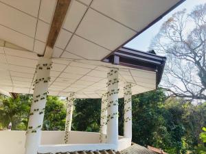 a white house with columns and a roof at Ashi Hostel Sigiriya in Sigiriya