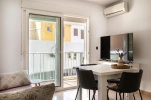a living room with a table and chairs and a television at Apto Primera Línea con Piscina - Guipas Beach in Puerto de Mazarrón