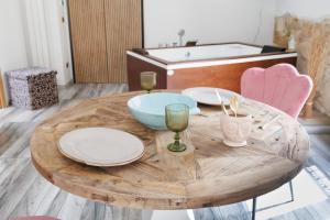 a wooden table with plates and glasses and a bath tub at Ire' Luxury Suite in Avola +21 photos