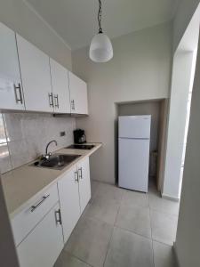 a kitchen with white cabinets and a white refrigerator at Musses Studios in Minia